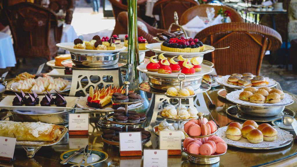 Afternoon tea in the Winter Garden at the Llao Llao Hotel featuring trays with desserts and bite-sized sandwiches. 