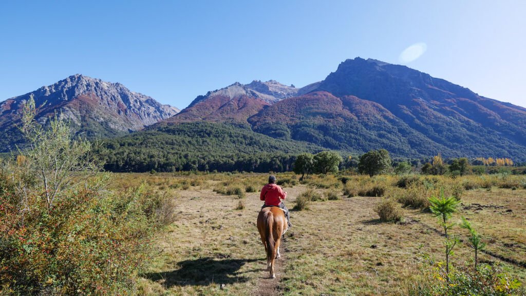 A traveller horseback riding in Bariloche at the foothills of the Andes Mountains. 