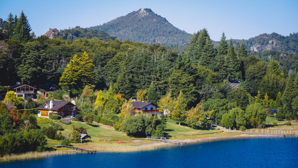 Lakeside homes built in the alpine style in Bariloche with views of forests Cerro Campanario in the background.