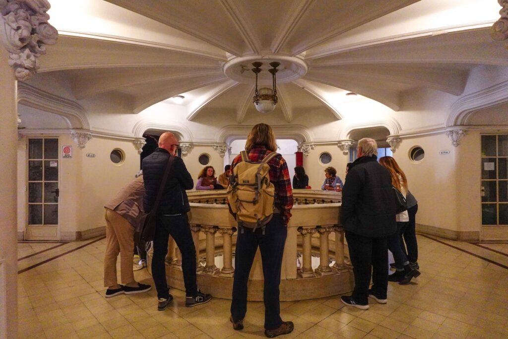 Guided group tour of Palacio Barolo standing on the fourth floor and looking down the central balcony 