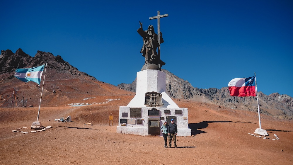 The Argentine and Chilean flags fly on either side of the Christ Redeemer of the Andes statue.