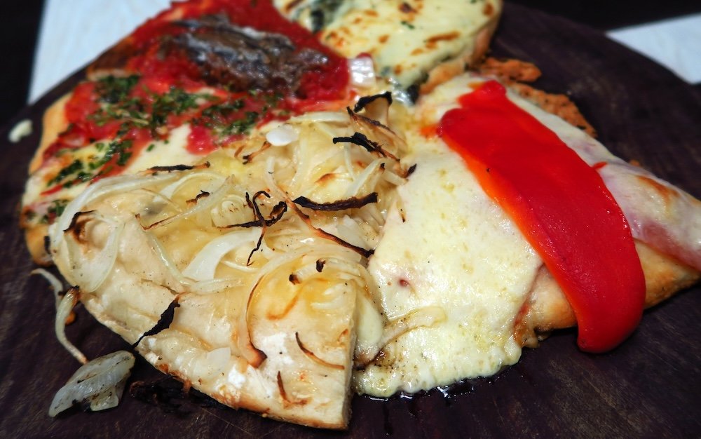 As assortment of pizza slices at an Argentine pizzeria.