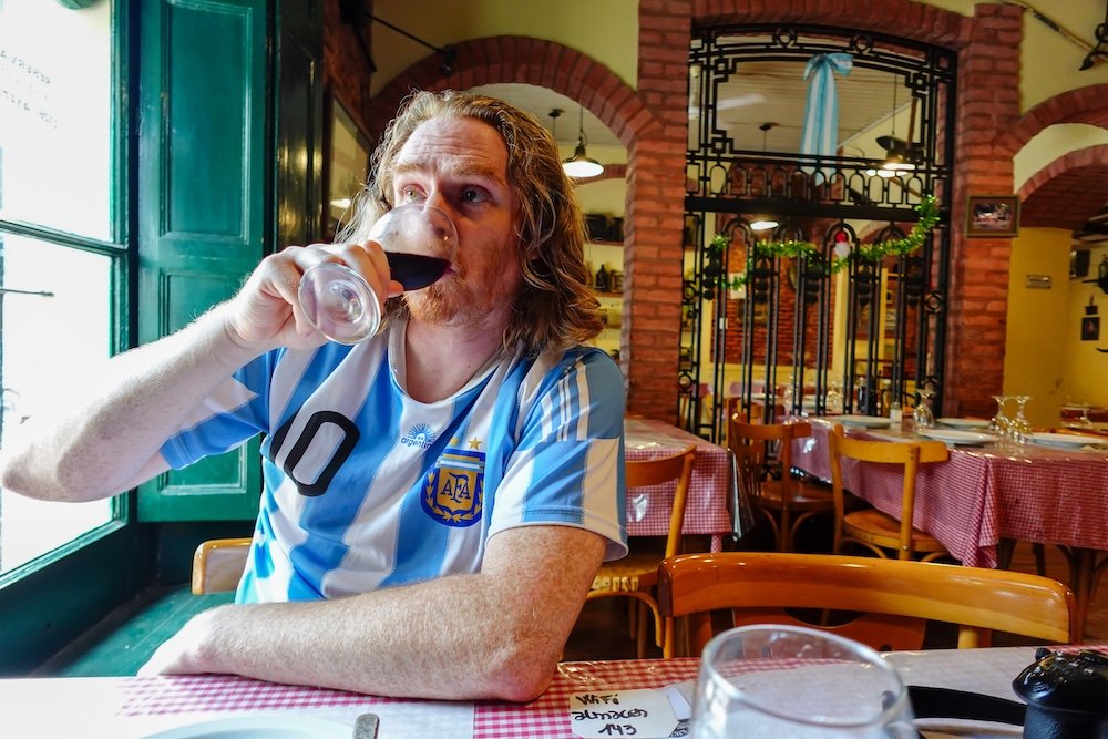 Samuel wearing the Argentina football jersey and drinking Malbec wine