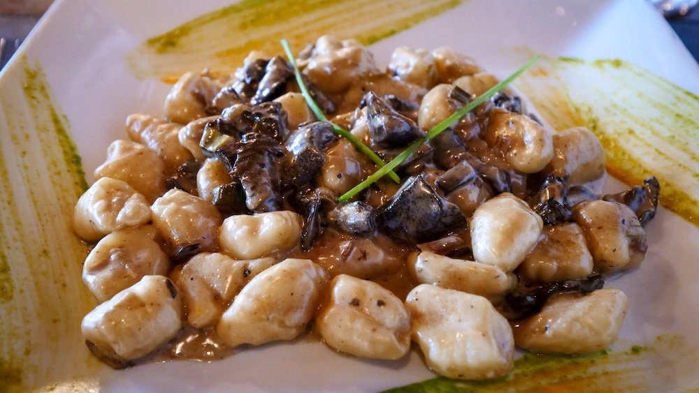 Plate of ñoquis served in a creamy mushroom sauce.