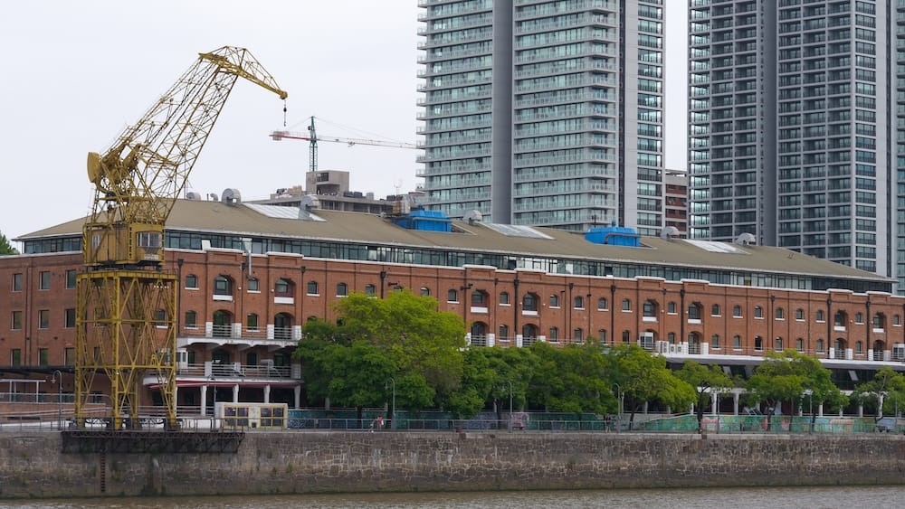 Red brick warehouses and yellow cranes can be seen along the old loading docks in the former port of Puerto Madero
