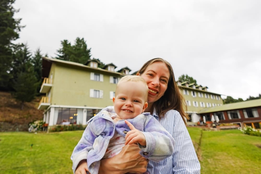 Audrey holding Aurelia in her arms and smiling at the camera during our hotel stay.