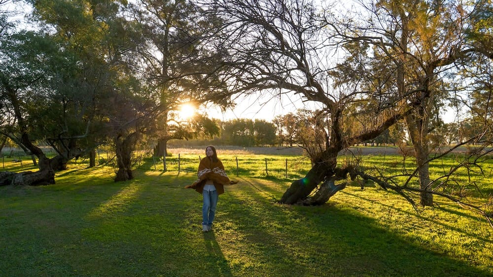 Audrey wearing a poncho and strolling around the property at sunset.