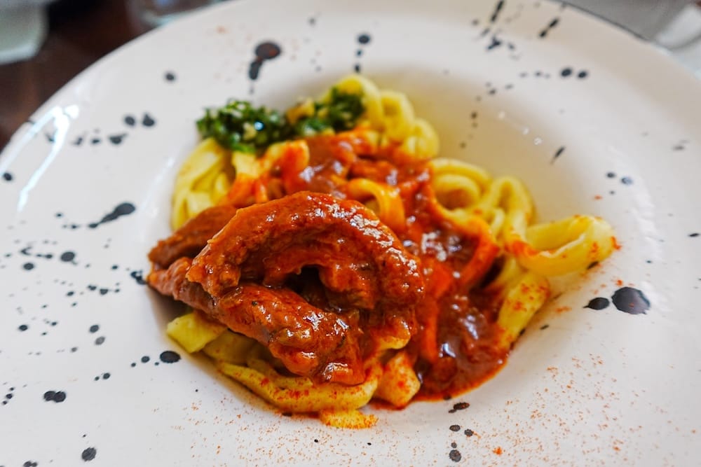 Homemade pasta with tomato sauce and pieces of beef.