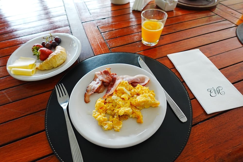 Scrambled eggs, bacon, fresh fruit and orange juice for breakfast.