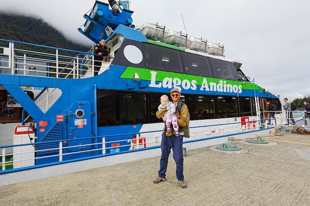 Sam standing in front of the Lagos Andinos catamaran at the port in Petrohué, Chile during our Andean Crossing trip.
