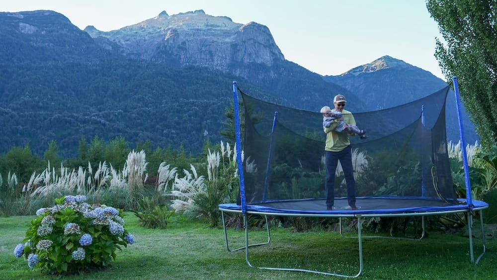 Samuel and baby bouncing on the trampoline at sunset at Hotel Natura Patagonia in Peulla, Chile.