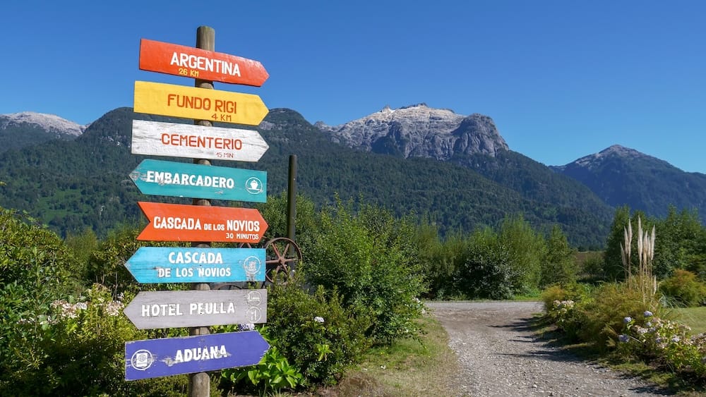 Wooden sign pointing to various landmarks and attractions in Peulla, Chile.