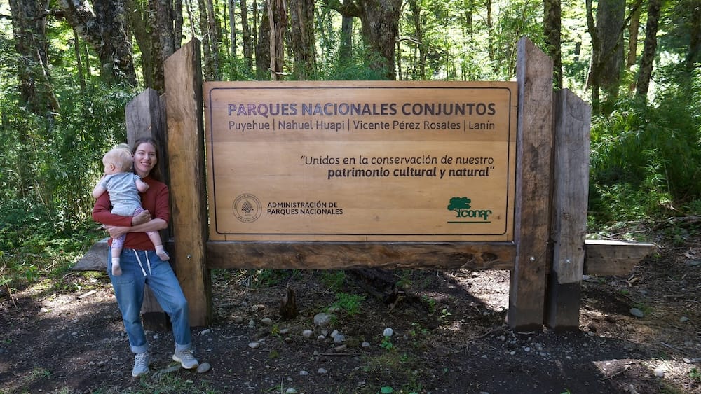 Audrey and baby posing next to the Vicente Perez Rosales National Park sign on the Andean Crossing journey.